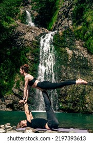 Acro Yoga. Young Man Holds His Girlfriend In Forest Near  Waterfall. Active Lifestyle Concept.