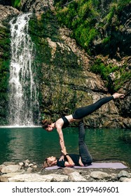 Acro Yoga. Young Man Holds His Girlfriend In Forest Near  Waterfall. Active Lifestyle Concept.