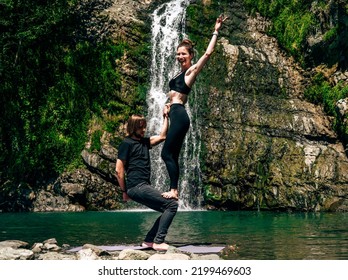 Acro Yoga. Young Man Holds His Girlfriend In Forest Near  Waterfall. Active Lifestyle Concept.