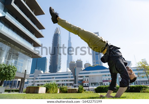 Acrobat keep\
balance one the hands with blurred Dubai cityscape. Concept of\
modern, business and unlimited possibility\
