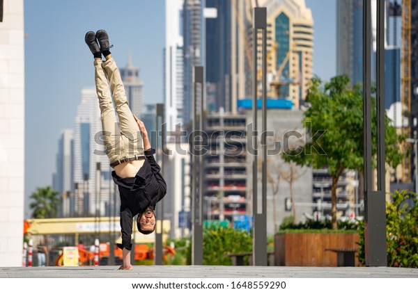 Acrobat keep\
balance one the hands with blurred Dubai cityscape. Concept of\
modern, business and unlimited possibility\
