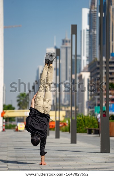 Acrobat keep
balance one the hands with blurred Dubai cityscape. Concept of
modern, business and unlimited possibility
