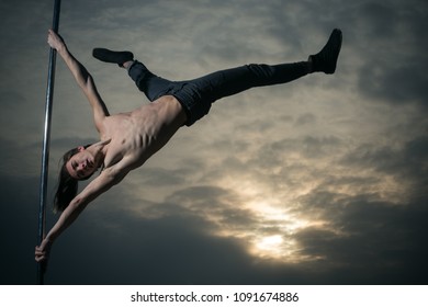acrobatic elements of man dancing on pole. acrobatic elements of pole dancer in sunset
