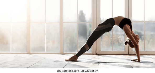 Acrobatic yoga girl making bridge over big panoramic window, stretching at home, free space - Powered by Shutterstock