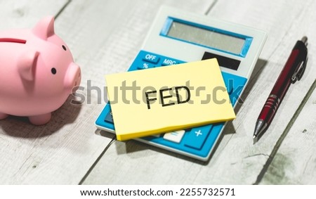 The acronym EDF written on a piece of paper lying on top of a calculator. A piggy bank on a wooden table in the composition. Economy and finance.
