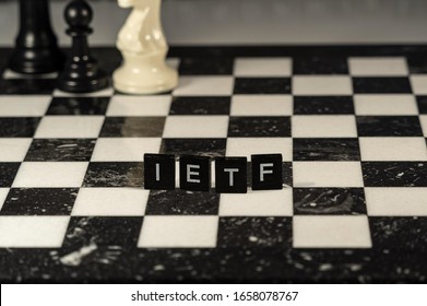 The Acronym IETF For Internet Engineering Task Force Concept Represented By Black And White Letter Tiles On A Marble Chessboard With Chess Pieces