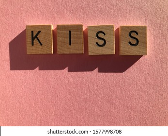 Acronym KISS, Keep it Simple Stupid, in wooden alphabet letters on a pink background with copy space
