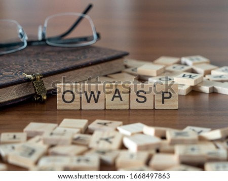 the acronym owasp for Open Web Application Security Project concept represented by wooden letter tiles on a wooden table with glasses and a book