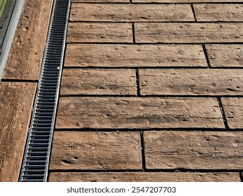 across the path there is a channel with a metal grid for drainage interlocking paving. the water is drained from the surface into the gutter and further into the rain sewer - Powered by Shutterstock