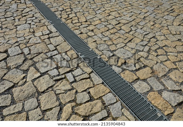 across the path\
there is a channel with a metal grid for drainage interlocking\
paving. the water is drained from the surface into the gutter and\
further into the rain\
sewer