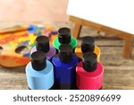 Acrylic paints of different colors in bottles on table, closeup