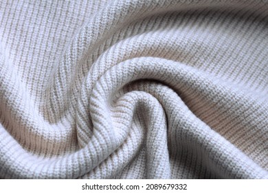 Acrylic textile texture background: white woolen fabric, sheep wool clothing, soft warm clothes. Knitted tissue of pullover, twisted folds of plaid, pastel sweater