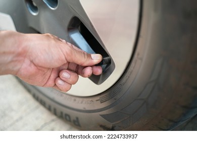 Action of a driver hand is checking on a wheel cap valve to ensure air pressure of the car tire before driving. Transportation service and equipment object, selective focus.