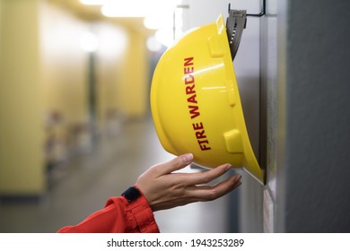 Action of fire fighter is taking a "Fire Warden" safety yellow hardhat helmet that hang on the wall, Response for emergency situation. Close-up and selective focus at the human's hand. - Powered by Shutterstock