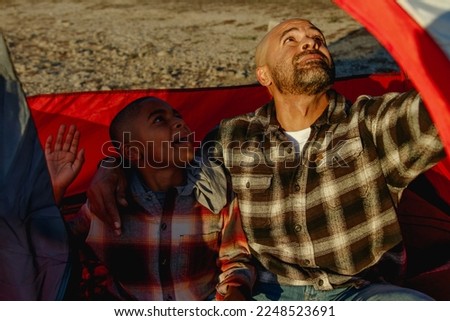 Action image of young son heloing his father swat a bug in the red tent