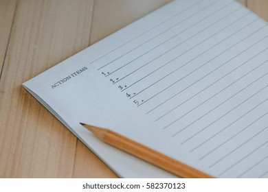 Action Items Write Down On Notebook By Pencil Put On Wooden Table