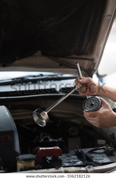 Action of man hands holding oil filter\
cap wrench and automotive oil filter preparing to change the new\
one, car fixing and maintenance service\
concept.
