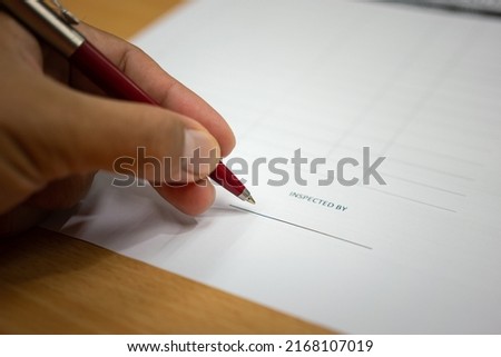 Action of the manager is using a luxury ballpoint pen to endorsing name as inspected person on the report paper. Business finance or industrial working scene. Selective focus. 