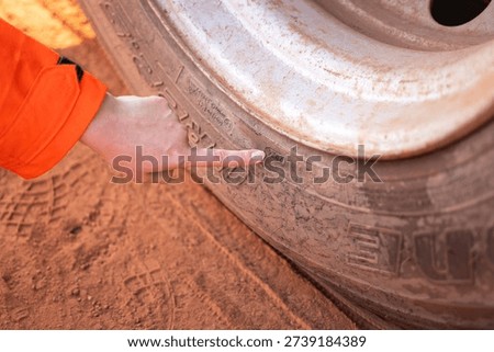 Action of a mechanic is checking on the trailer wheel condition and manufacturing date, verify for safety transporation. Close-up and selective focus at the hand.