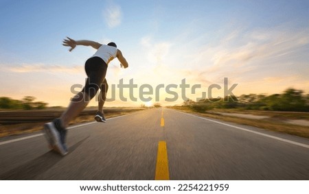 Action motion blur of a man running on country road with sunrise background.