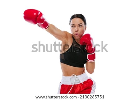 In action, motion. Young girl, professional boxer practicing in boxing gloves isolated on white studio background. Sport, competition, show, power, action concept. Copy space for ad, text