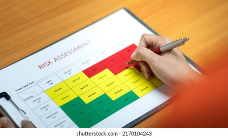 Action Of A Person Is Using Ballpoint Pen To Marking On The Risk Assessment Matrix Table At 