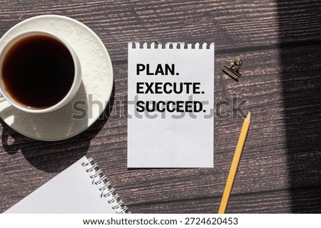 Action Plan Plan, Execute, Succed writing on notebook. Notebook on desk with coffee cup and a pen.
