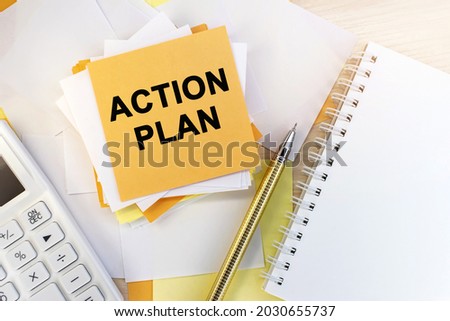 the action plan is written on a stack of note sheets. A notepad and a pen with a white calculator. Business concept