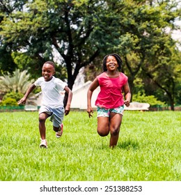 Action Portrait Of African Kids Playing And Running Together In Park.