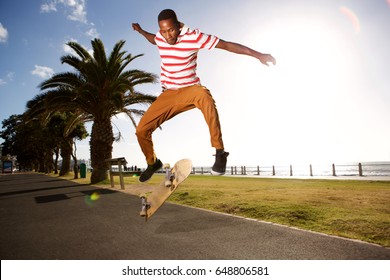 Action portrait of young male skateboarder doing a flip trick on road outside - Powered by Shutterstock