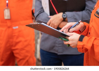 Action Of Safety Audit And Inspection Team Is Making A Discussion On The Paperwork With Colleague. Close-up And Selective Focus At Personal 's Hand.