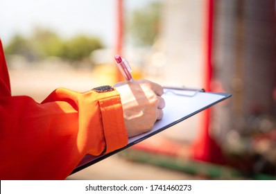 Action Of Safety Officer Or Supervisor Is Taking Note During Safety Audit In Oil Field Operation, Close-up And Selective Focus At People's Hand. Photo Is Appiled With Orange Shade Sun Light Effect.