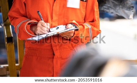 Action of safety officer is wirtinng and check on checklist document during safety audit and inspection at drilling site operation. Industrial expertise occupation photo.