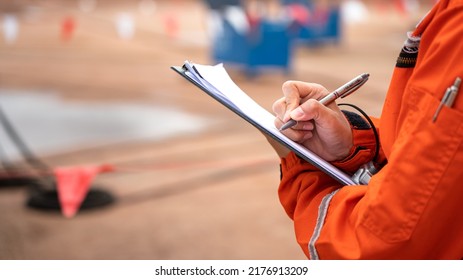 Action of safety officer is writing and check on checklist document during safety audit and inspection at drilling site operation. Industrial expertise occupation working scene. - Shutterstock ID 2176913209