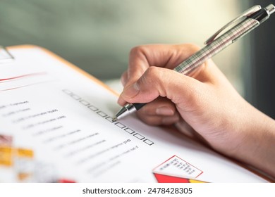 Action of a safety supervisor hand is checking on checklist of chemical and hazardous material form to verify the risk with blurred background of factory storage workplace. Industrial working scene. - Powered by Shutterstock