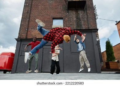 Action Shot Of All Male Breakdance Team Doing Jumps In Urban City Setting