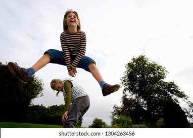 Action shot of children in mid-air playing leapfrog in garden