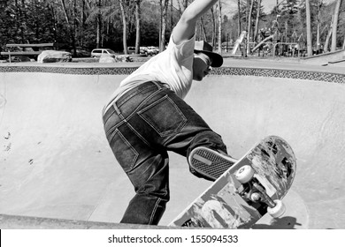 Action shot of a skateboarder skating in a concrete skateboarding bowl at the skate park. High contrast black and white. - Powered by Shutterstock