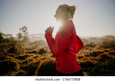 Action Shot Of Young Athletic Female Running In The Park, Back Light