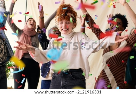 Action shot of young white woman celebrating International Women's Day with friends and ticker tape