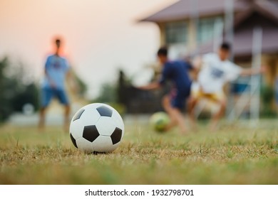 Action sport outdoors of a group of kids having fun playing soccer football for exercise in community rural area under the twilight sunset.