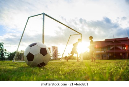 Action sport outdoors of kids having fun playing soccer football for exercise in community rural area under the twilight sunset sky. Picture with copy space.