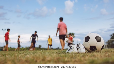 Action sport outdoors of kids having fun playing soccer football for exercise in community rural park.