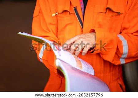 Action of a supervisor pointing on document paper for discussion during a safety audit and operation commisionning. Indsutrial worker people photo. Selective focus at the people hand.
