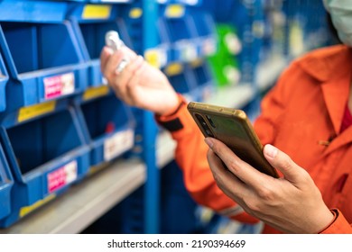 Action of the worker is checking item inventory by using smartphone. Industrial and technology working scene, close-up and selective focus at phone's part.