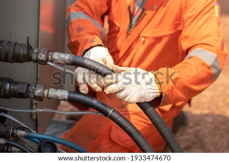 Action of worker hand is connecting and checking to high-pressure hydraulic hose line of power pack engine. Industrial working action photo, Close-up and selective focus. 
