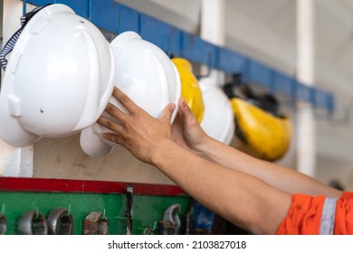 Action of a worker is taking a safety helmet or hardhat from the hanging rack, ready to working in the industrial concept photo. Close-up and selective focus. - Powered by Shutterstock