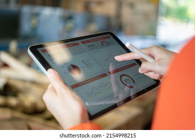 Action of a working is using tablet to review factory report with blurred background of warehouse. Business management and technology concept photo. Close-up and selective focus at human's hand part. - Powered by Shutterstock