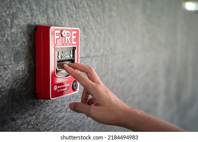 Activate fire alarm trigger system which is installed on granite wall of the building. Human action scene photo, selective focus.