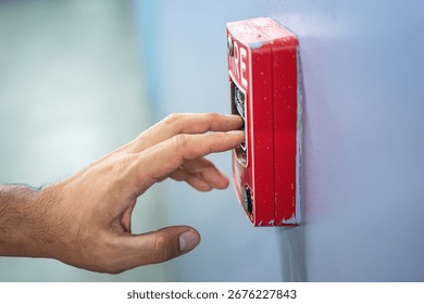 Activate fire alarm trigger system which is installed on building wall. Human action scene photo, selective focus.